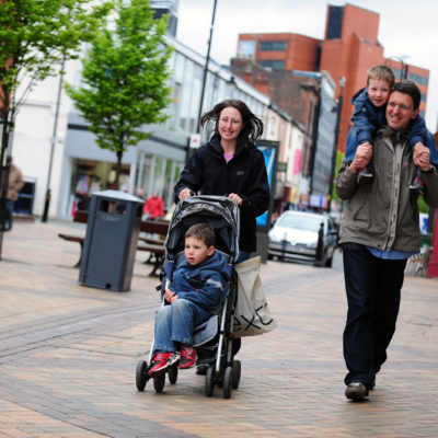 parents and children walking in town centre with pushchair and child on dads shoulders