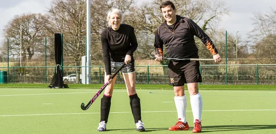 Two adults holding hockey sticks