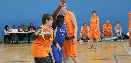 Adults playing Walking Basketball in a sports hall