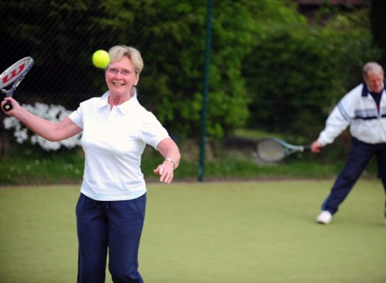 Senior lady hitting a tennis ball