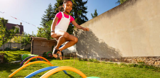 Young girl jumping over hurdles
