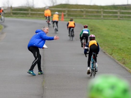 Instructor encouraging children on a road cycling training course