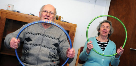 Older couple in seated exercise class Vernon and Glennis holding hula hoops