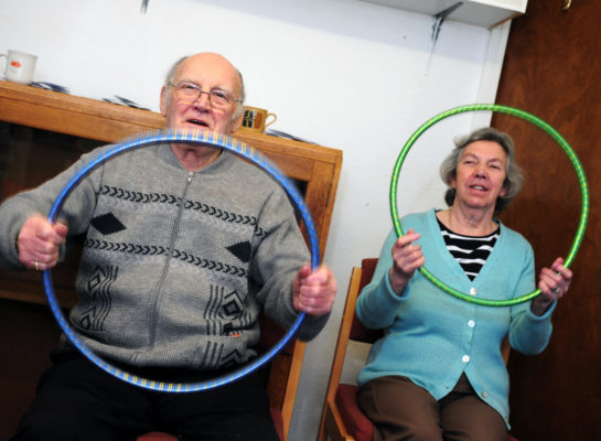 Older couple in seated exercise class Vernon and Glennis holding hula hoops