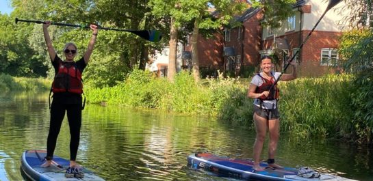 2 women on paddlebaods on a canal